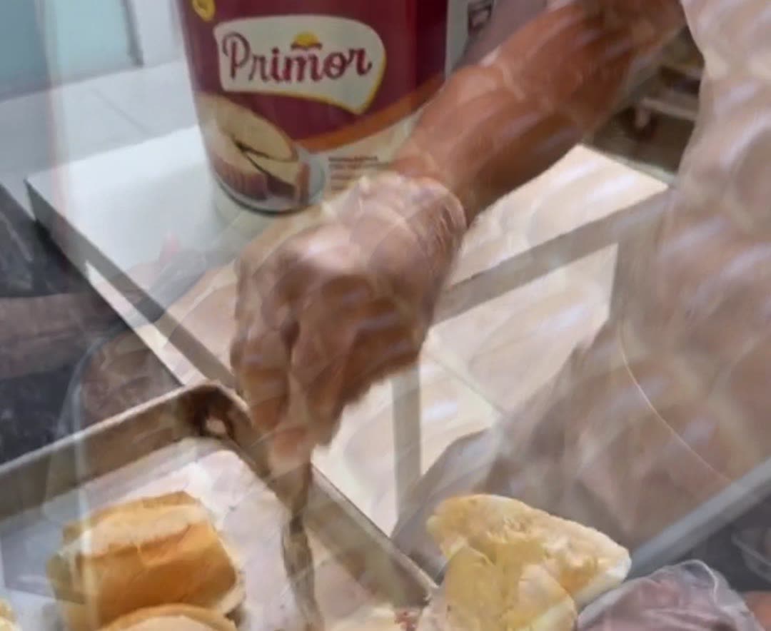 Pão francês sendo recheado com manteiga